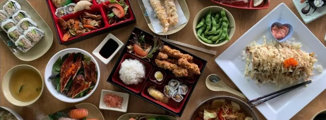 An overhead spread of Blessings dishes: bento, eel salad, edamame, an aburi roll, ramen and miso