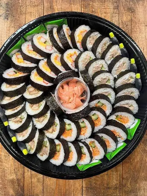 A round platter of mixed nori rolls with pickled ginger in the middle